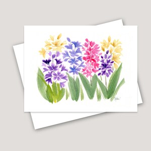 May include: Watercolor painting of a bouquet of hyacinths in shades of purple, pink, and yellow. The flowers are arranged in a row, with the stems and leaves extending to the sides. The painting is signed "Yellen" in the bottom right corner.