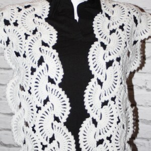 May include: White crocheted shawl with a delicate, lacy pattern. The shawl is draped over a black shirt.