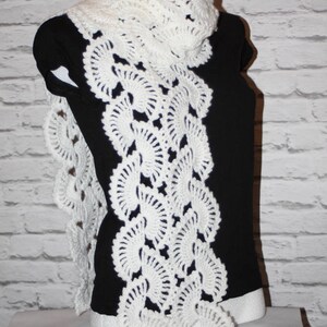 May include: White crocheted scarf with a lacy design featuring a series of circular patterns. The scarf is draped over a black mannequin.