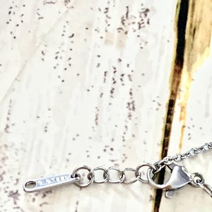 K&ouml;nnte beinhalten: Nahaufnahme einer silbernen Kettenkette mit einem Karabinerverschluss. Die Kette besteht aus kleinen, runden Gliedern.