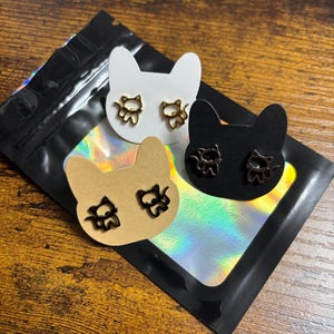 Une paire de boucles d'oreilles en acier inoxydable chaton en couleurs or, argent noir, carte avec tête de chat scintillante, sac cadeau souvenir amusant nouveauté original