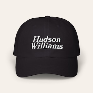 Peut inclure: Casquette de baseball noire avec le texte "Hudson Williams" brodé en blanc. La casquette a une visière incurvée et une couronne structurée. Un chapeau de style classique, adapté aux tenues décontractées.