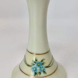 May include: A white ceramic flower frog with a gold rim and blue forget-me-not flowers painted on the base.