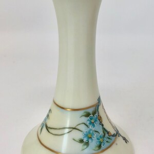 May include: A white ceramic flower frog with a gold rim and blue forget-me-not flowers painted on the base.