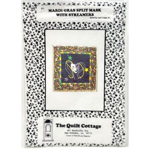 May include: A package featuring a Mardi Gras split mask design with streamers. The design includes a mask, stars, and streamers in purple, green, and gold on a dark background. The package is labeled "Mardi Gras Split Mask with Streamers" and includes the company name "The Quilt Cottage."