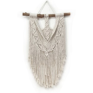 Large neutral macrame wall hanging on a crepe myrtle branch.