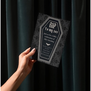 May include: A black and grey invitation card with a coffin-shaped design and the text "RIP to my 30s". The card includes details for a birthday celebration, featuring a bat graphic. The card is held against a dark green backdrop.