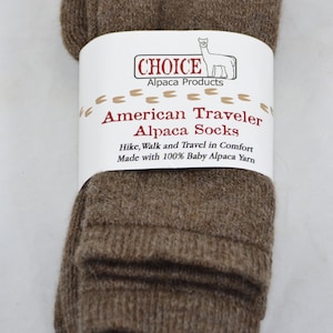 May include: Brown alpaca socks folded in a package. The package has a white label with the text "CHOICE Alpaca Products American Traveler Alpaca Socks Hike, Walk and Travel in Comfort Made with 100% Baby Alpaca Yarn".
