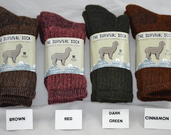 May include: Four pairs of alpaca wool socks in brown, red, dark green, and cinnamon. The socks are folded and labelled "The Survival Sock" with a picture of an alpaca and the text "Made in the USA with US Grown Alpaca".