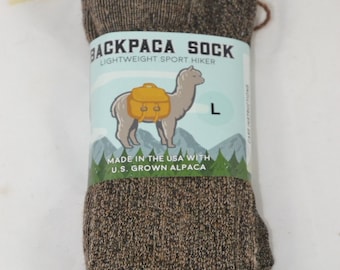 May include: A pair of brown alpaca hiking socks with a label that reads "Backpaca Sock Lightweight Sport Hiker" and features a cartoon alpaca wearing a backpack. The label also says "Made in the USA with U.S. Grown Alpaca" and "L".