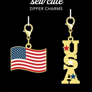 May include: Two gold zipper charms with a patriotic theme. One charm features a red, white, and blue American flag. The other charm is gold with the letters "USA" in gold with red, white, and blue stars.