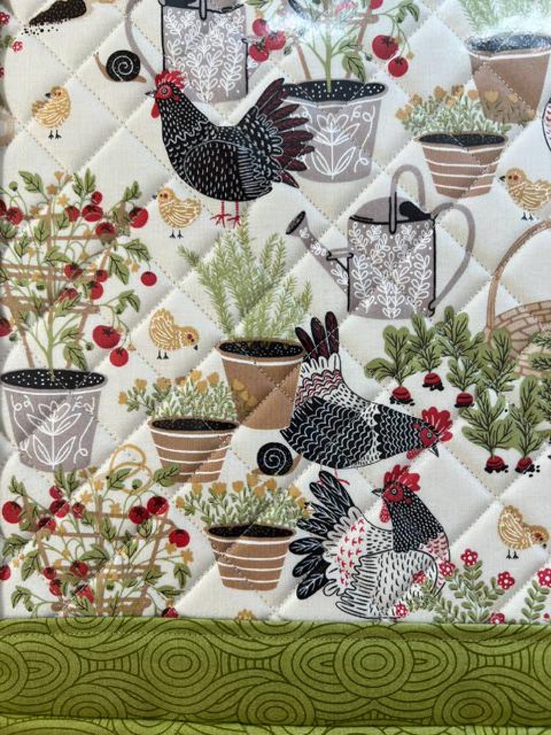Pu&ograve; includere: Un tessuto trapuntato a tema giardino. Il design presenta polli, piante in vaso, pomodori e un annaffiatoio. La tavolozza dei colori comprende crema, verde, rosso, marrone e nero. Il tessuto viene probabilmente utilizzato per la cucina o l'arredamento della casa.