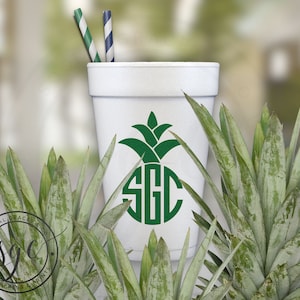 May include: White foam cup with a green pineapple design and the monogram "SGC" in a circle. The cup is surrounded by green pineapple plants.