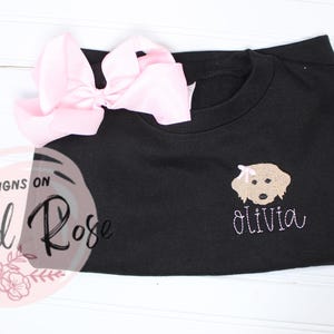 May include: Black sweatshirt with a gold embroidered dog and the name "Olivia" in white embroidery.