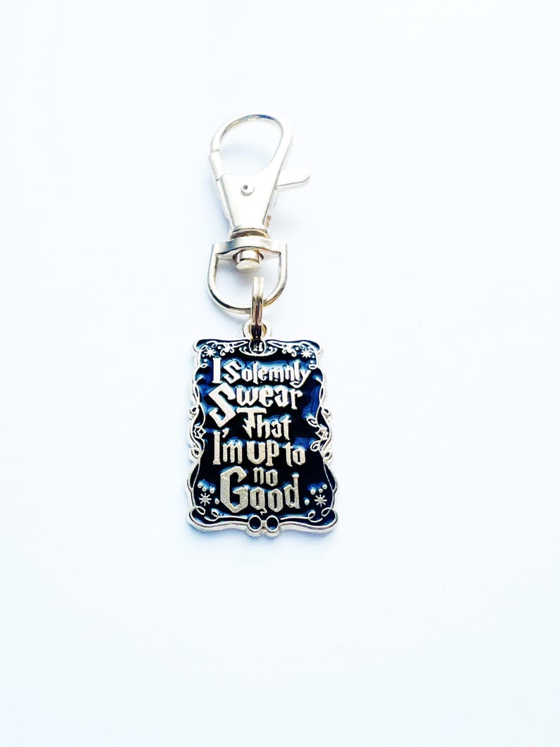 May include: A rectangular keychain with the text "I Solemnly Swear That I'm Up To No Good" in white lettering on a dark blue background. The keychain has a silver-coloured clasp.