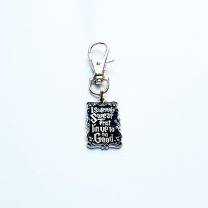 May include: A rectangular keychain with the text "I Solemnly Swear That I'm Up to No Good" in white script on a dark blue background. The keychain has a silver-coloured metal border and a clasp.