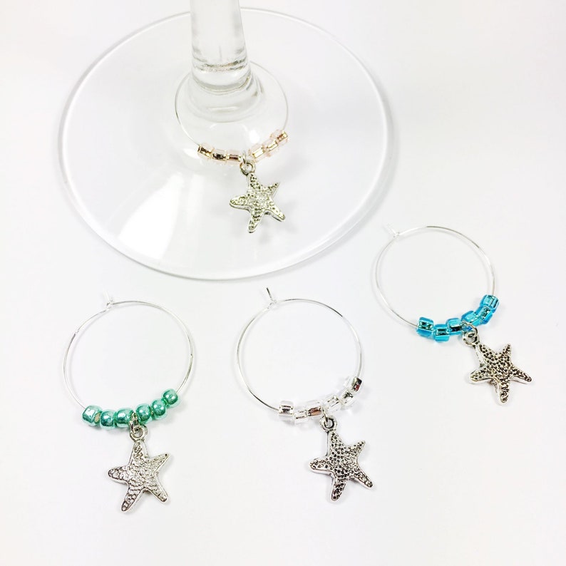 May include: Four silver wine glass charms with starfish charms and beaded chains. The charms are in turquoise, green, clear, and pink.