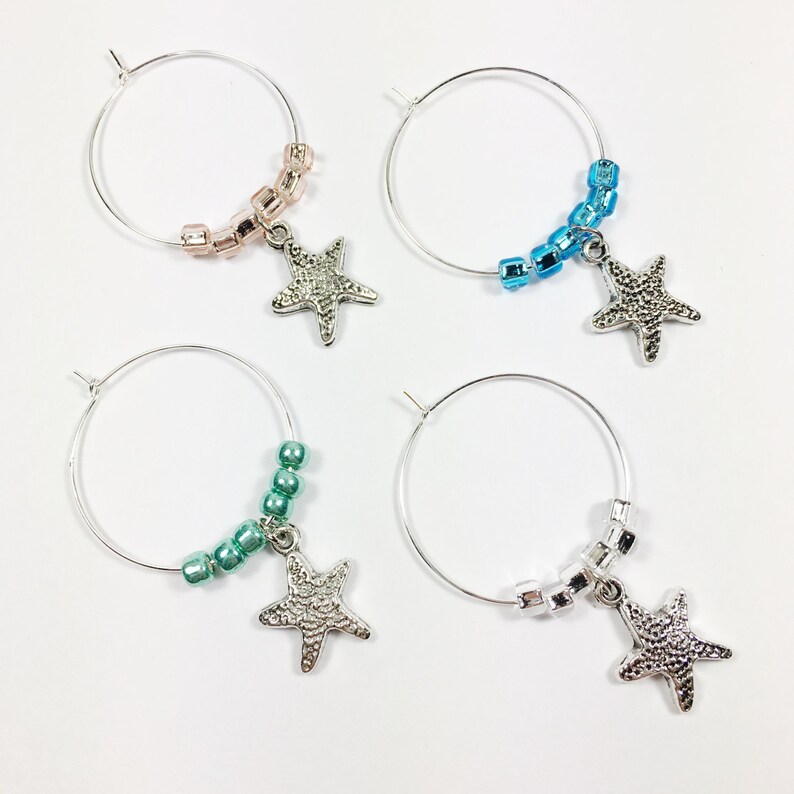 May include: Four silver wine glass charms with starfish pendants and beaded strands in pink, blue, green, and clear colors.