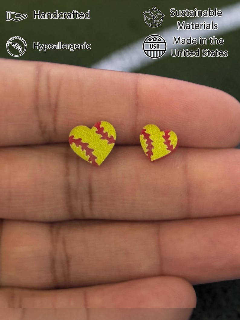 Fingers holding softball heart stud earrings