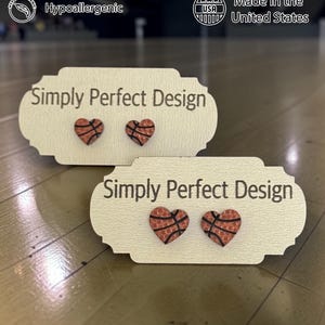Two sizes of basketball heart stud earrings on Simply Perfect Design cards in a gym