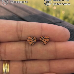 Basketball heart studs resting on fingertips to show size