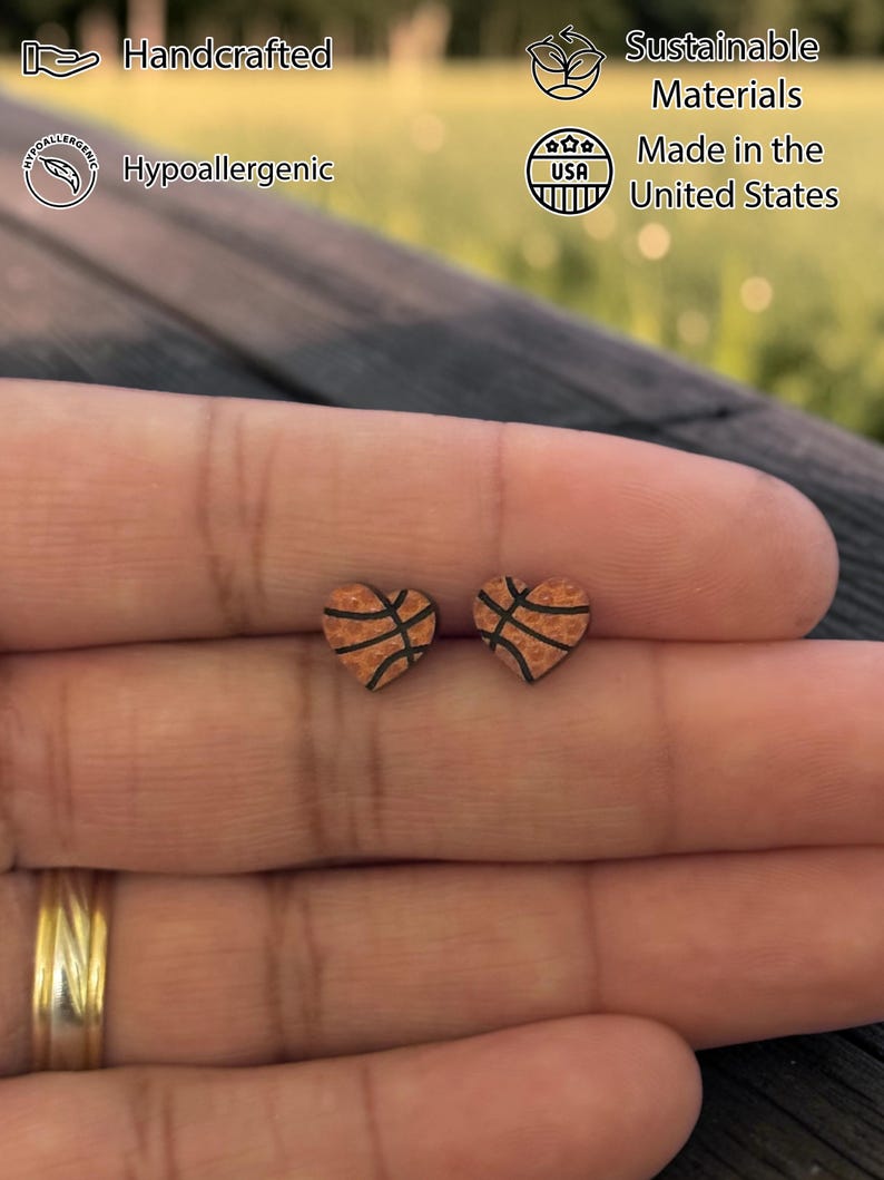 Basketball heart studs resting on fingertips to show size