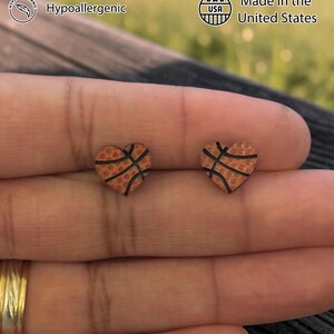 Fingers holding orange basketball heart stud earrings