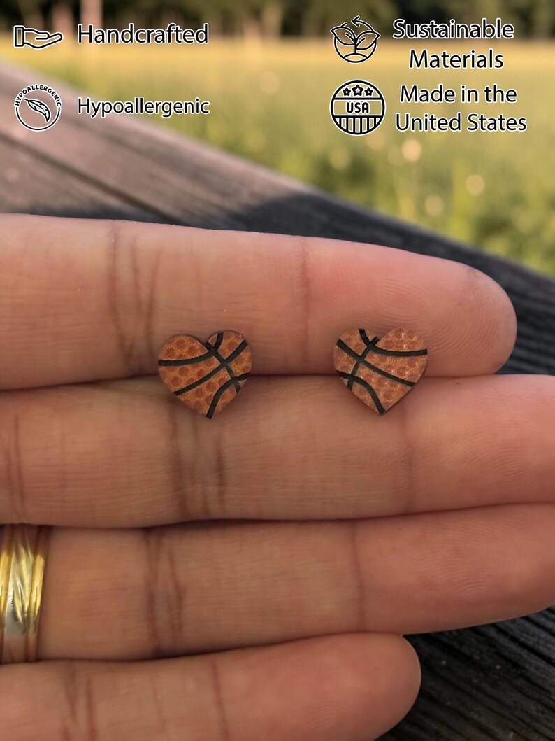 Fingers holding orange basketball heart stud earrings