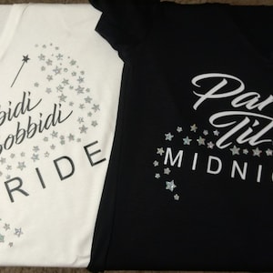 Op de afbeelding: Twee witte T-shirts met zwarte tekst en zilveren glittersterren. Het eerste shirt zegt "Bibbidi Bobbidi Bride" en het tweede shirt zegt "Party Til Midnight" met een zilveren glitter-hak.