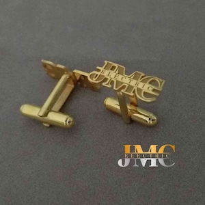 May include: Gold cufflinks with the text "IMC Electric" engraved on them.