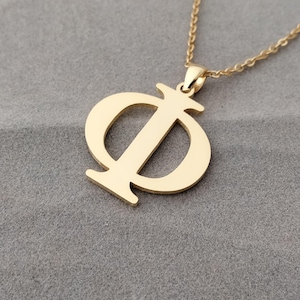 Op de afbeelding: Een goudkleurige ketting met een hanger in de vorm van de Griekse letter Phi (Φ). De hanger heeft een solide, gestileerd ontwerp met een centrale verticale lijn en gebogen boven- en onderdelen. De ketting is een delicaat, geschakeld ontwerp.
