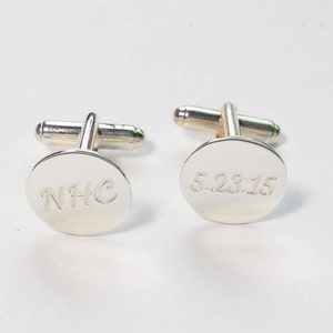 May include: A pair of silver cufflinks with engraved initials "NHC" on one cufflink and the date "5.28.15" on the other cufflink.