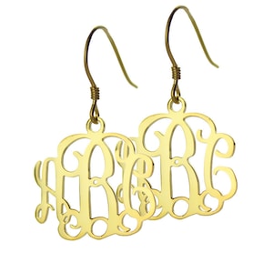 May include: Gold-toned monogram earrings with a delicate, cursive script design. The earrings feature a hook closure.