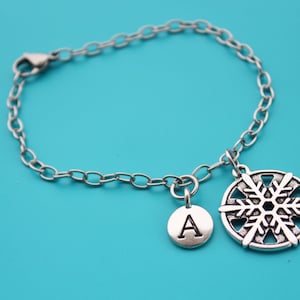 May include: A silver chain bracelet with a snowflake charm and a charm with the letter A.