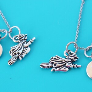 Puede incluir: Dos collares de plata con dijes. Un dije es una bruja montando una escoba con un disco de plata que dice "7". El otro dije es una bruja montando una escoba con un disco de plata que dice "R".