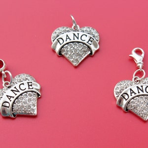May include: Three silver heart-shaped charms with rhinestones and the word "DANCE" on each. The charms are on a red background.