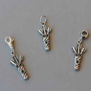 Può includere: Tre ciondoli in argento a forma di faretra di frecce, uno con chiusura a clip, uno con un anello per perline e l'ultimo con un anello a salto. Ogni ciondolo presenta un design dettagliato di frecce in una faretra.