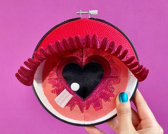 EYE HEART YOU |  Red fiber art sculpture of eye with heart iris and red eye lids, one-of-a-kind design handmade by artist, valentines decor