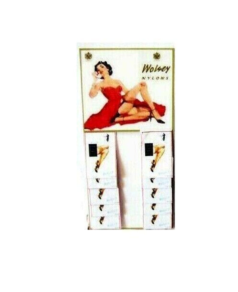 Puede incluir: Un expositor con un anuncio vintage de Wolsey Nylons con una mujer con un vestido rojo. El expositor tiene varias filas de tarjetas peque&ntilde;as con im&aacute;genes de piernas con medias.