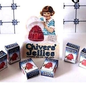 May include: A miniature set of six boxes of Chivers Jellies, a brand of jelly desserts. The boxes are blue and white with red and white illustrations of jelly desserts. The boxes are arranged in a semi-circle on a white surface. The boxes are labeled "Chivers Jellies".