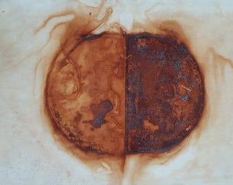 May include: A circular stain on a light-colored surface, divided vertically into two distinct halves. The left side features a smooth, light brown gradient, while the right side displays a dark, textured, and oxidized rust-colored pattern.