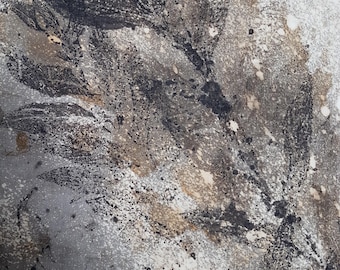 May include: A fabric surface featuring a botanical print with dark charcoal and brown leaf silhouettes. The design includes a speckled, distressed texture with white, gray, and tan splatters layered over the leaves, creating a weathered appearance.