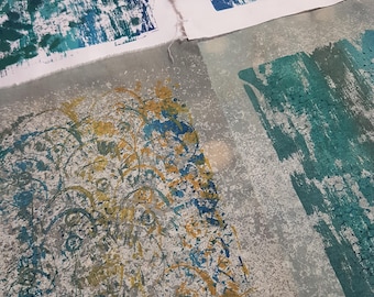 May include: Four rectangular fabric swatches featuring abstract prints in shades of teal, blue, and mustard yellow. The designs include textured brushstrokes, layered paint effects, and intricate swirling patterns on a light-colored textile base.