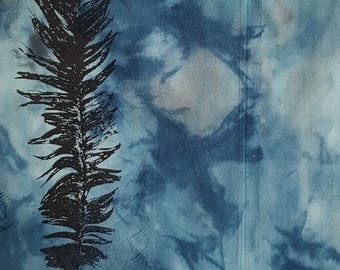 May include: A fabric surface featuring a tie-dye pattern in shades of blue and white. A prominent black feather graphic is printed on the left side. The material displays a subtle, tonal woven texture with vertical stitching lines visible on the right.