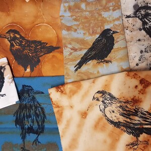 May include: Five pieces of fabric with different rust-coloured backgrounds and black crow illustrations. The crows are in various poses and sizes. The fabric is a natural material with a rough texture.