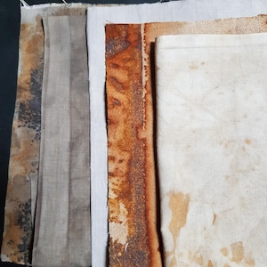 May include: A collection of fabric samples in beige, brown, and off-white hues. Some swatches feature mottled patterns and stains, while others are plain. The fabrics are arranged in a layered composition, displaying different textures and tones.