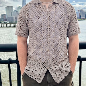 May include: A brown crochet shirt with a button-up front and short sleeves. The shirt is made of a lightweight, open-weave fabric.