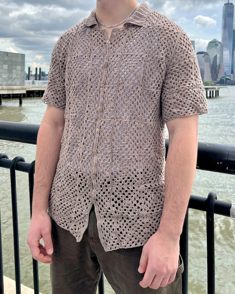 May include: A brown crochet button-up shirt with a short sleeve. The shirt is made of a lightweight, open weave fabric.