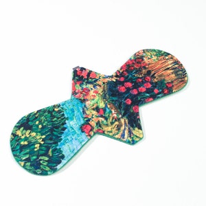 May include: A green reusable menstrual pad with a colorful floral print. The print features a variety of colors, including red, yellow, green, and blue.