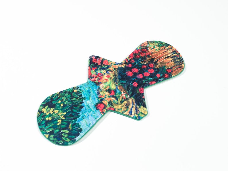 May include: A green reusable menstrual pad with a colorful floral print. The print features a variety of colors, including red, yellow, green, and blue.